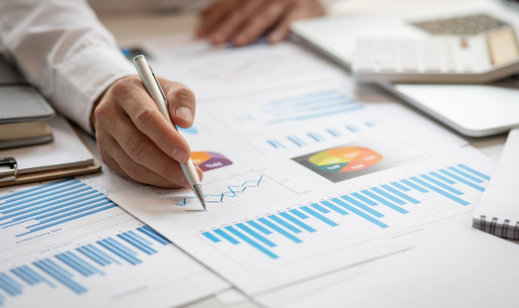 A photo of someone adding notes to graphs arrayed on a table.