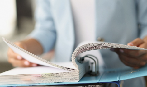 A photo of someone looking through a binder of paper.